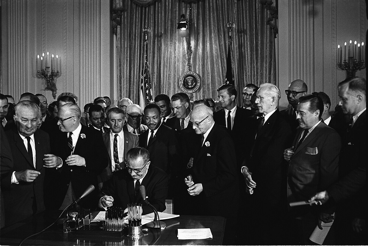 President Lyndon B. Johnson signing the Civil Rights Act on July 2, 1964, with Martin Luther King Jr. and others present.